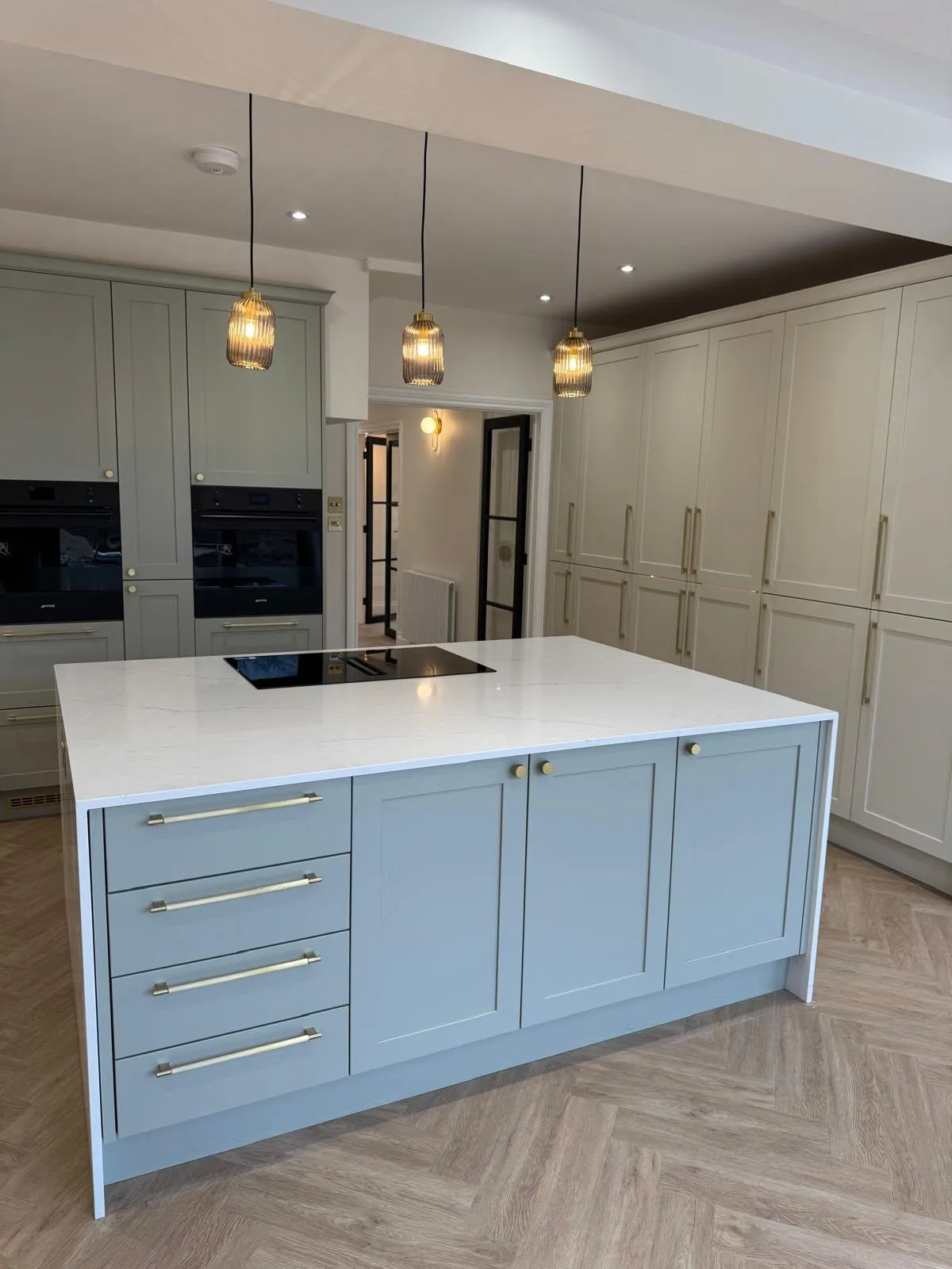 Kitchen island with waterfall worktop and tall pantry cabinets