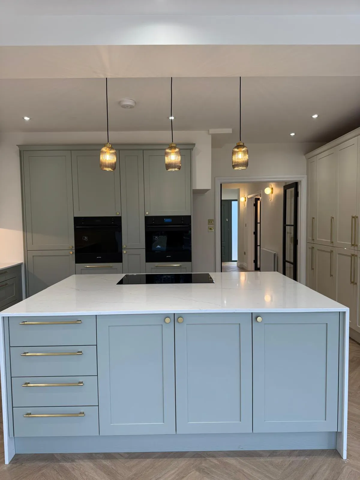 Kitchen island with induction hob, built-in ovens and brass handles