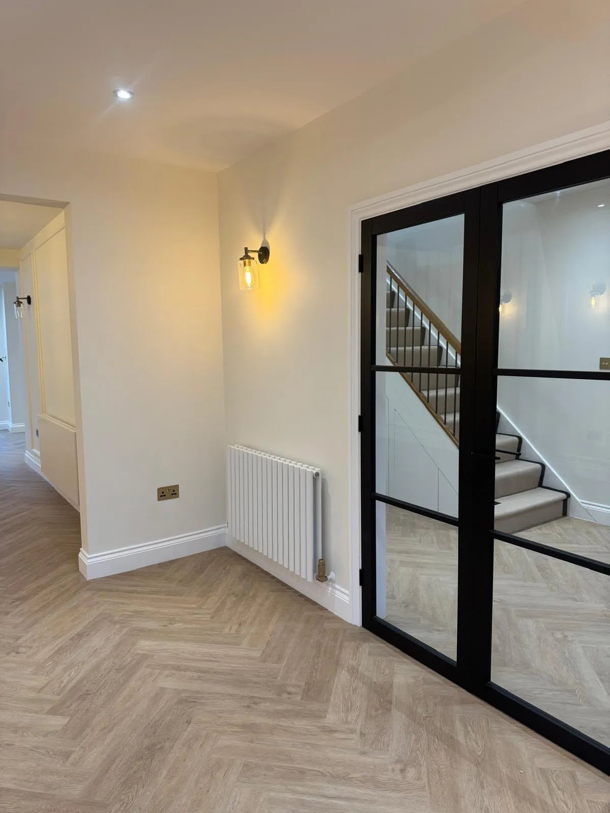Hallway with black glazed double doors, wall light and column radiator
