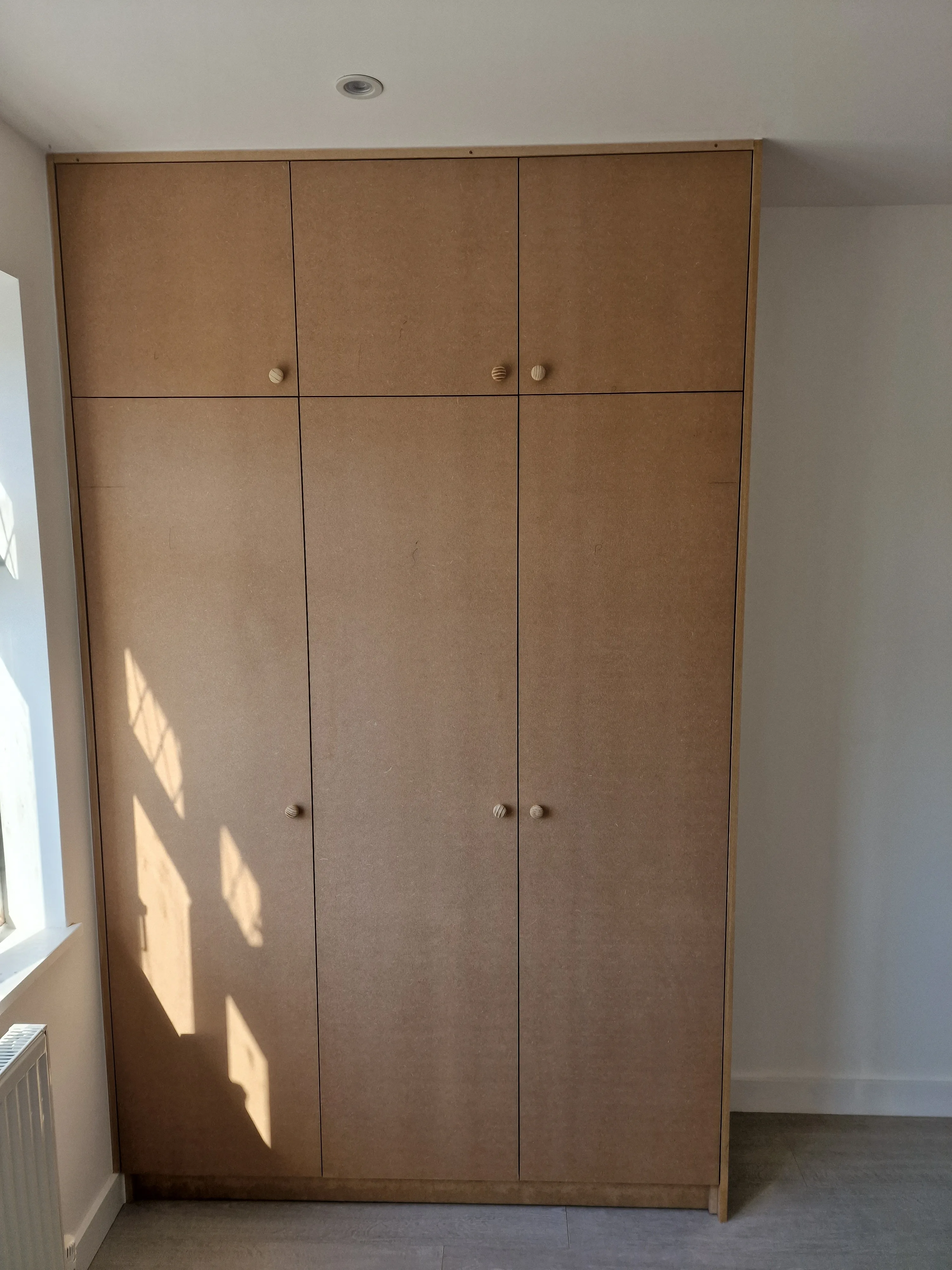 Wooden built-in wardrobe with minimalist design against a light wall