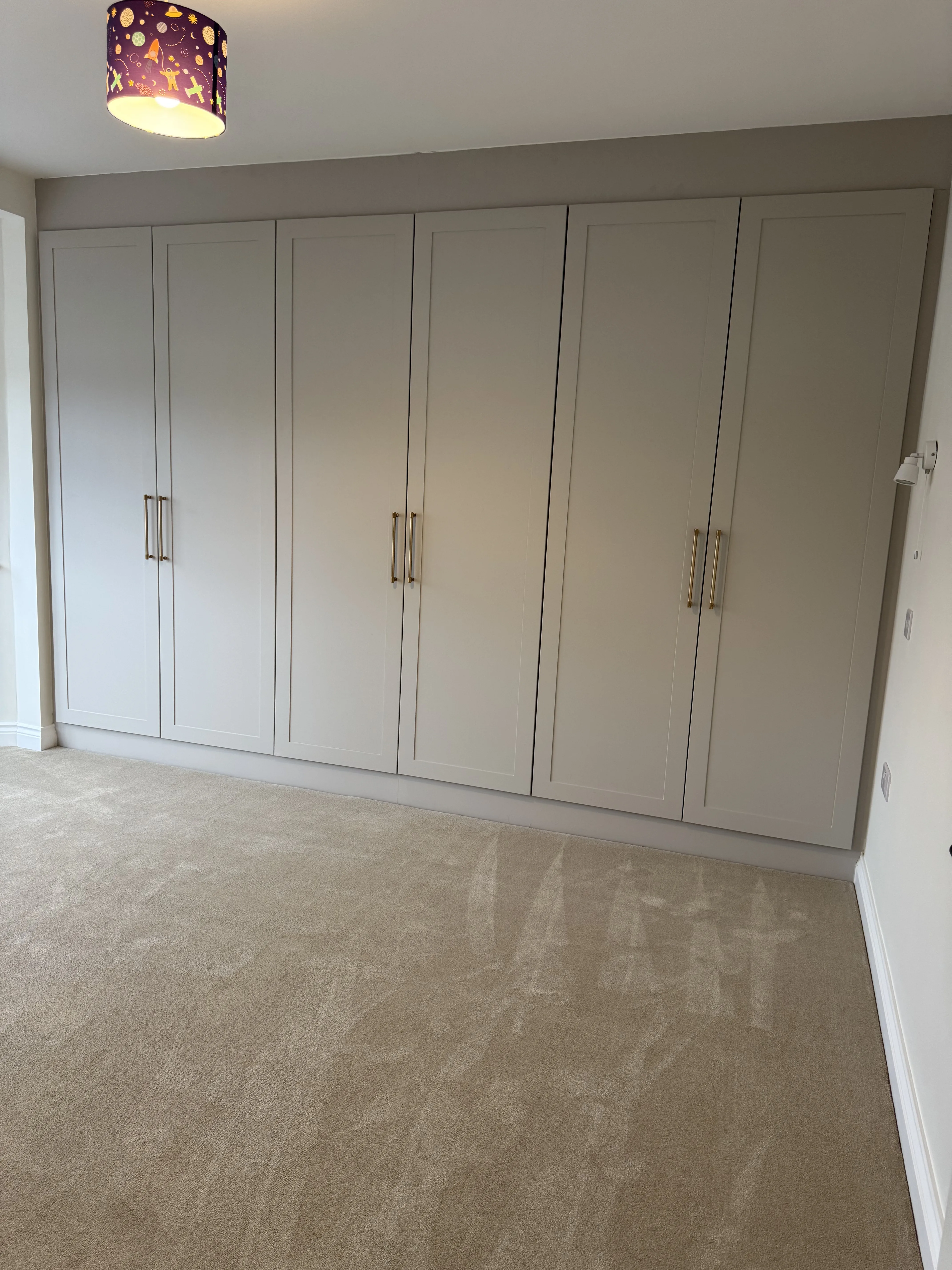 Built-in wardrobes in a modern bedroom featuring a soft color palette