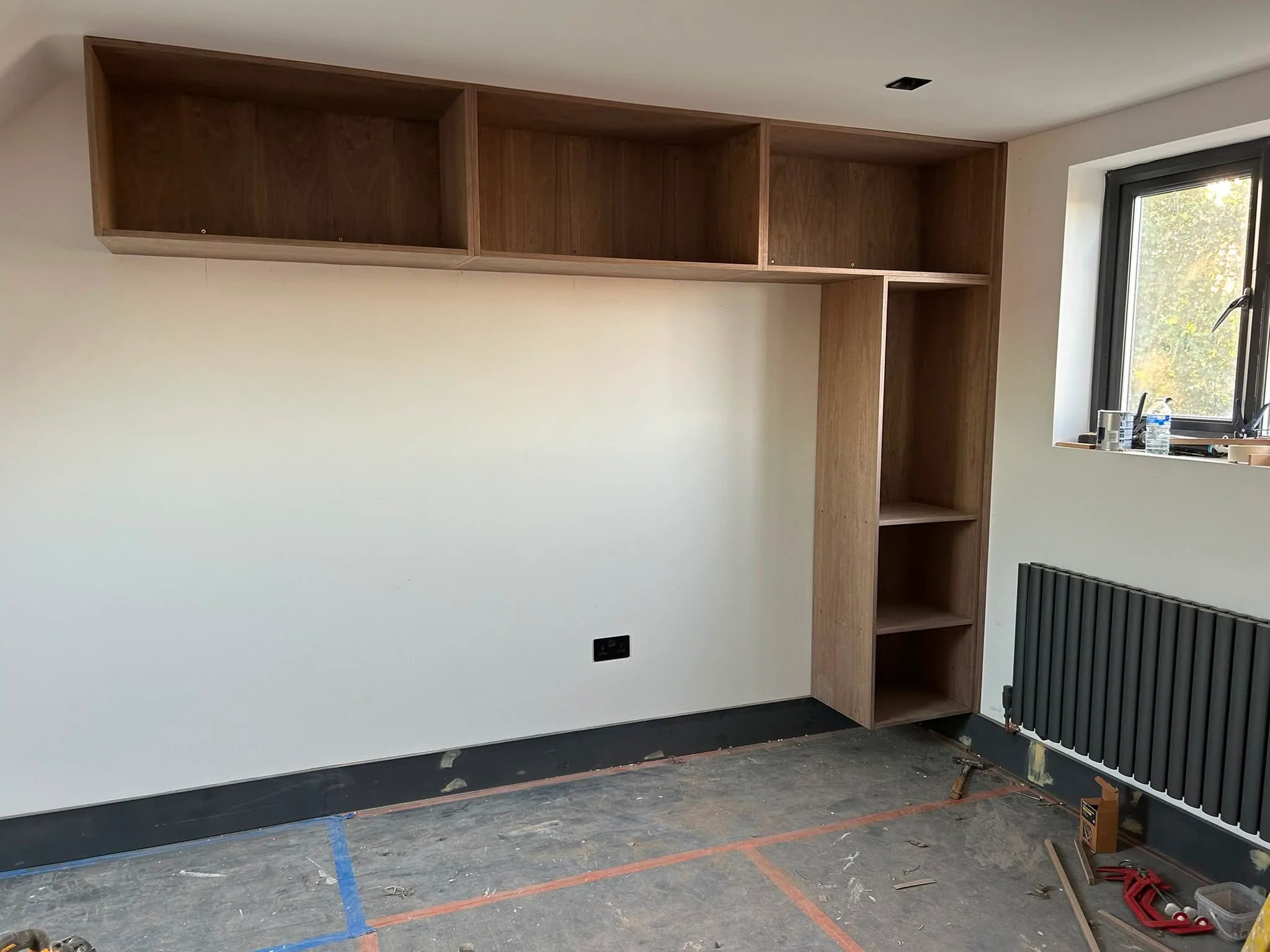 Interior view of a room showing a wooden built-in wardrobe installation in progress