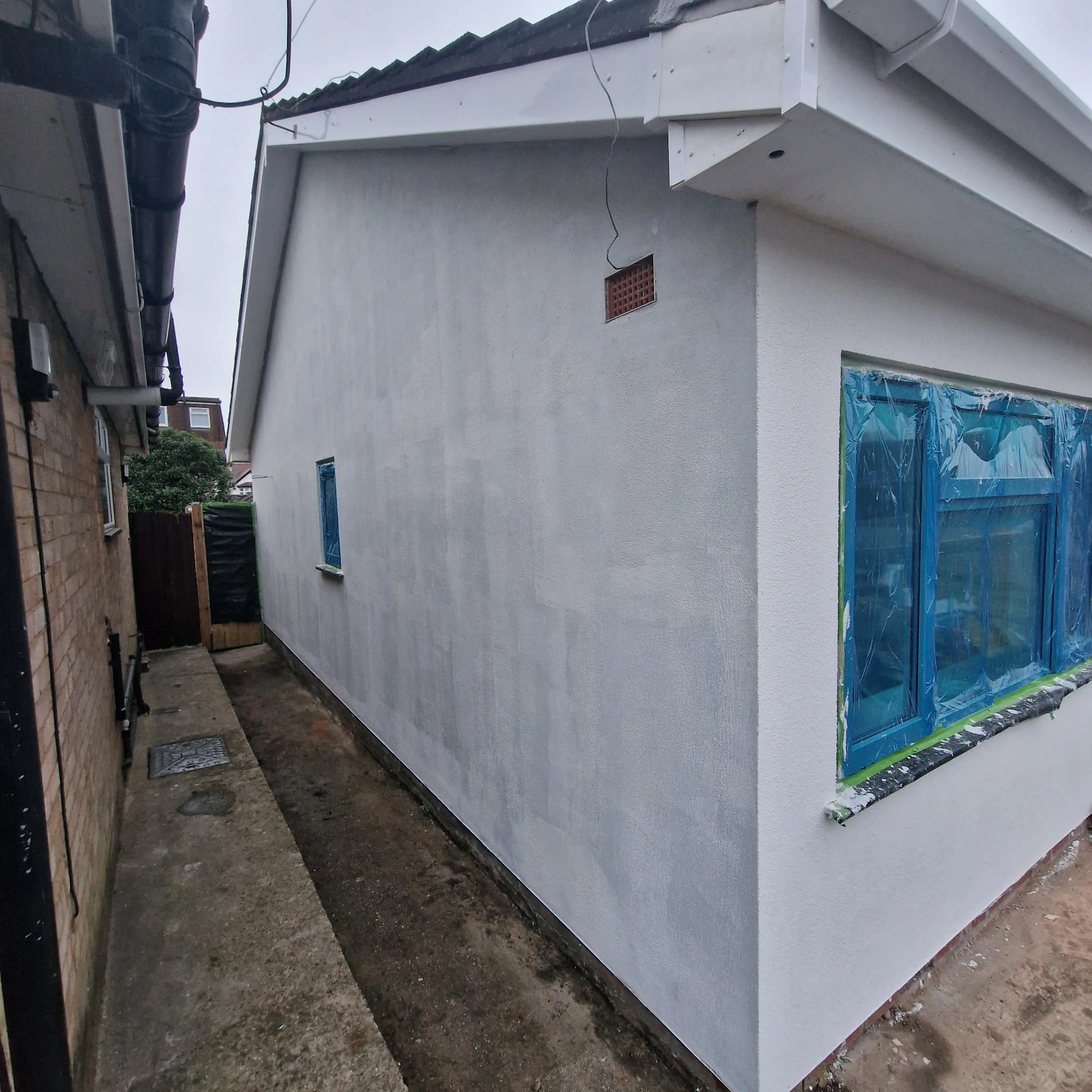 Exterior rendering of a house showing freshly applied plaster and window framing