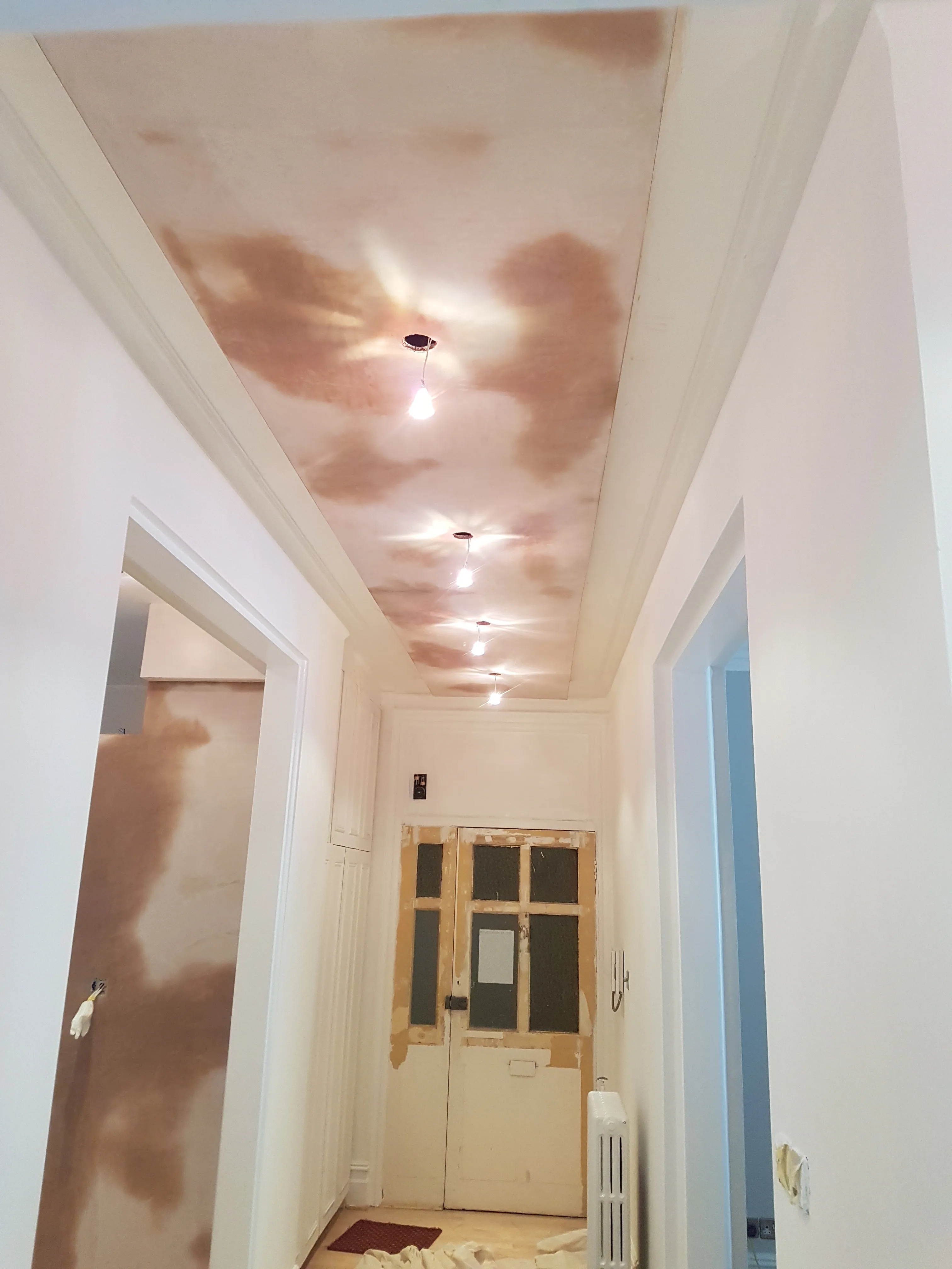 Newly renovated hallway with freshly painted white walls and a ceiling featuring exposed patches