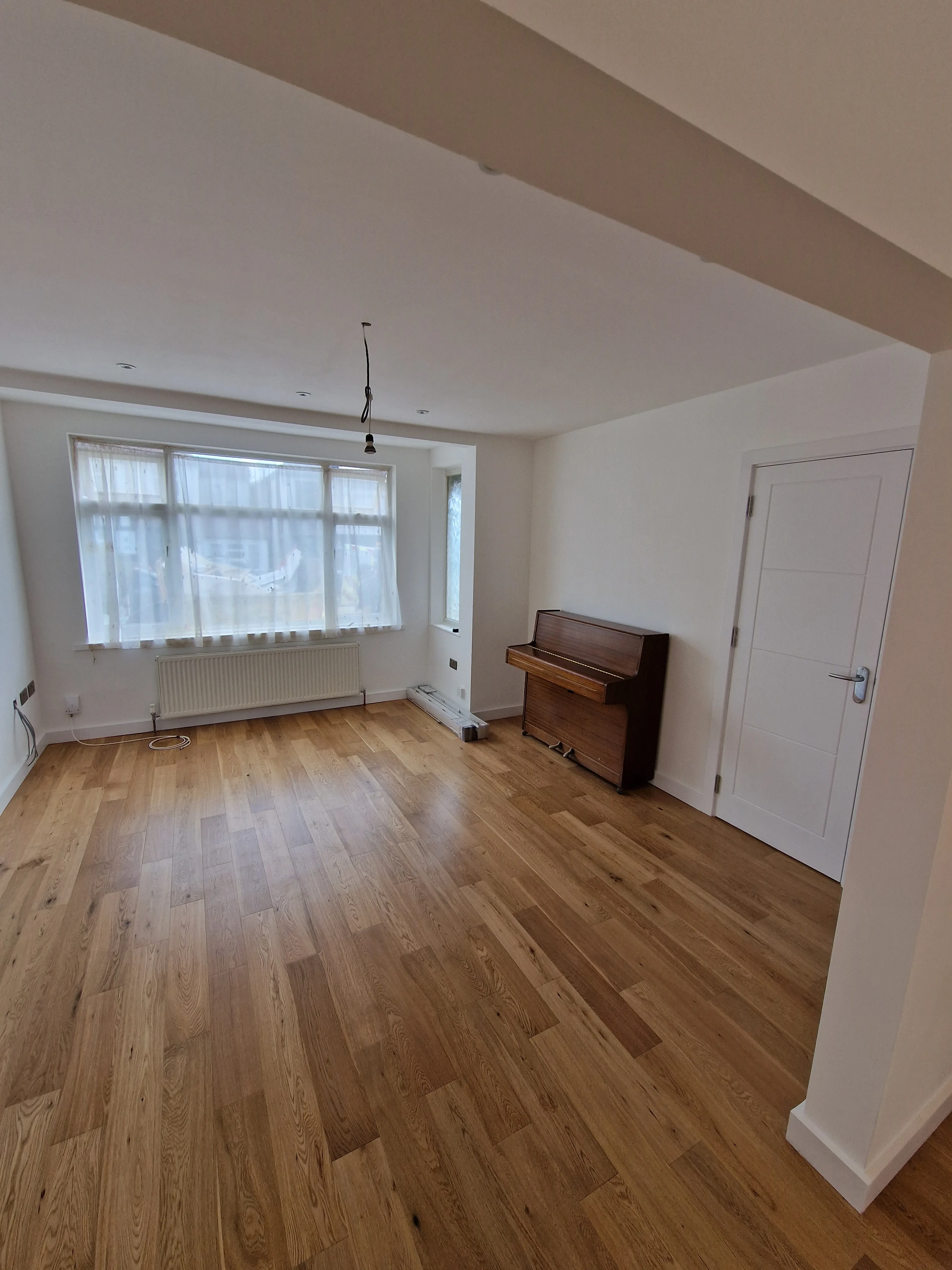Bright room with wooden floor and piano, showcasing home refurbishment service