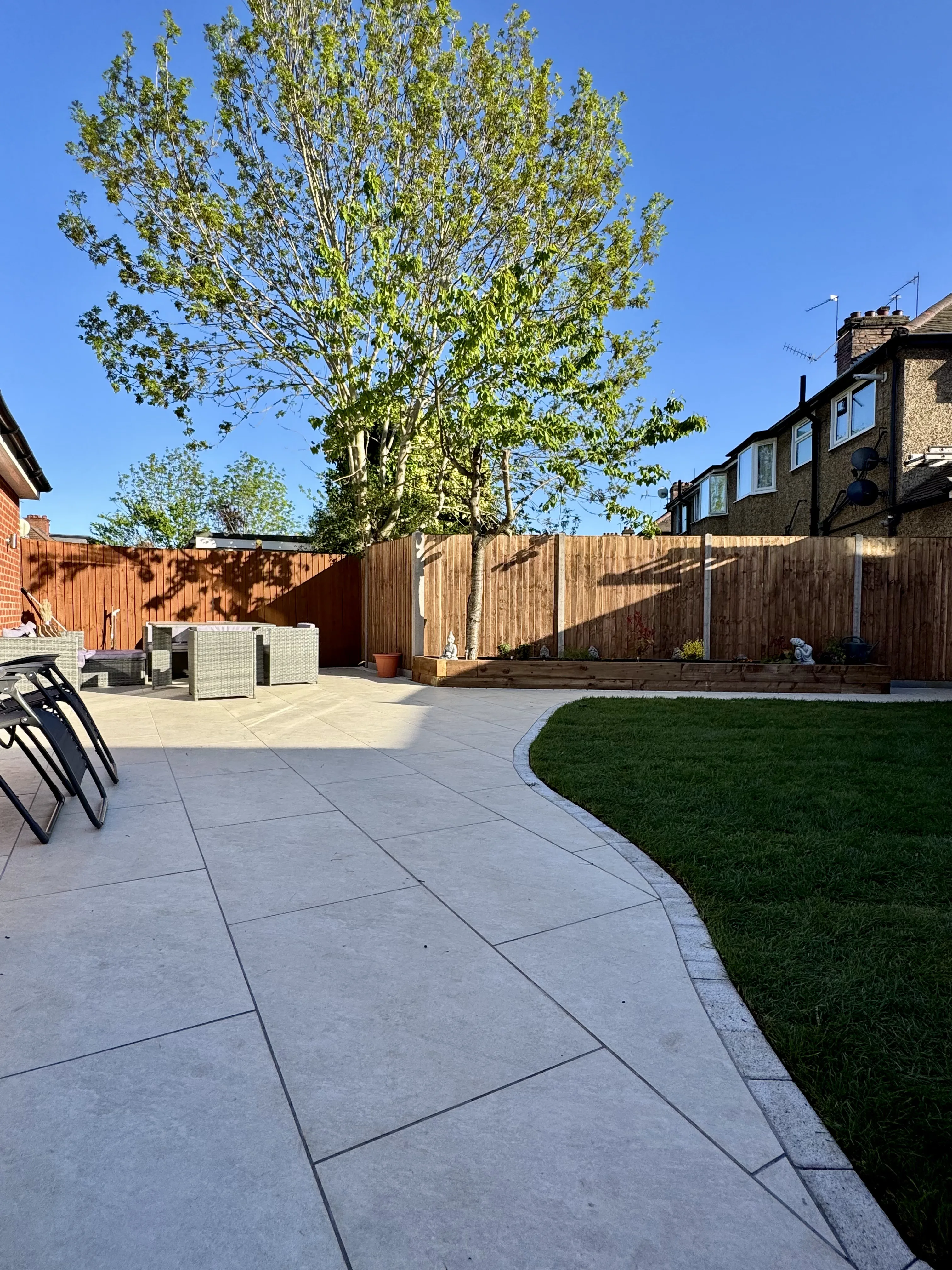 A well-designed garden landscaping with a patio area, seating, and greenery