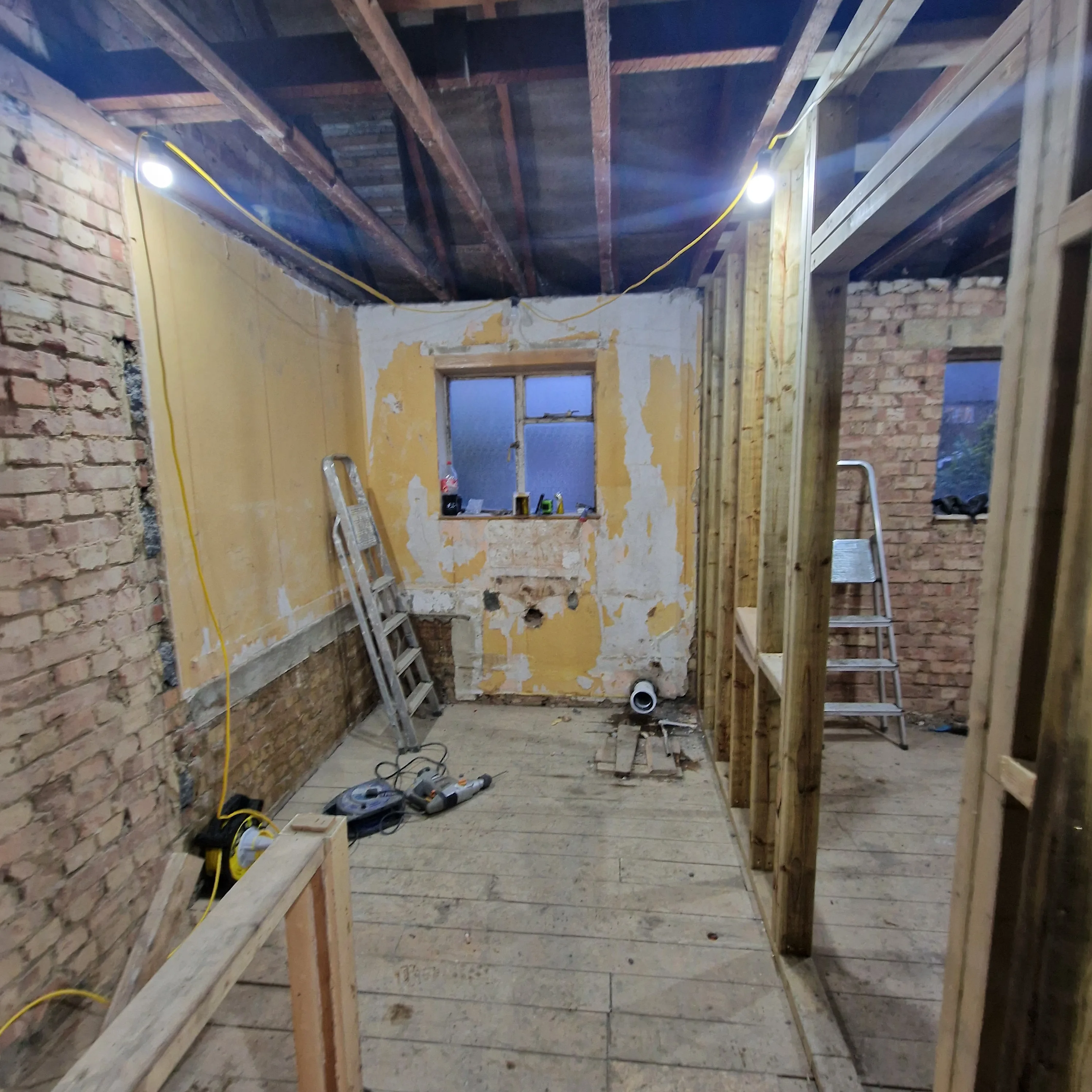 Interior of a house undergoing renovation with exposed brick walls and wooden framework