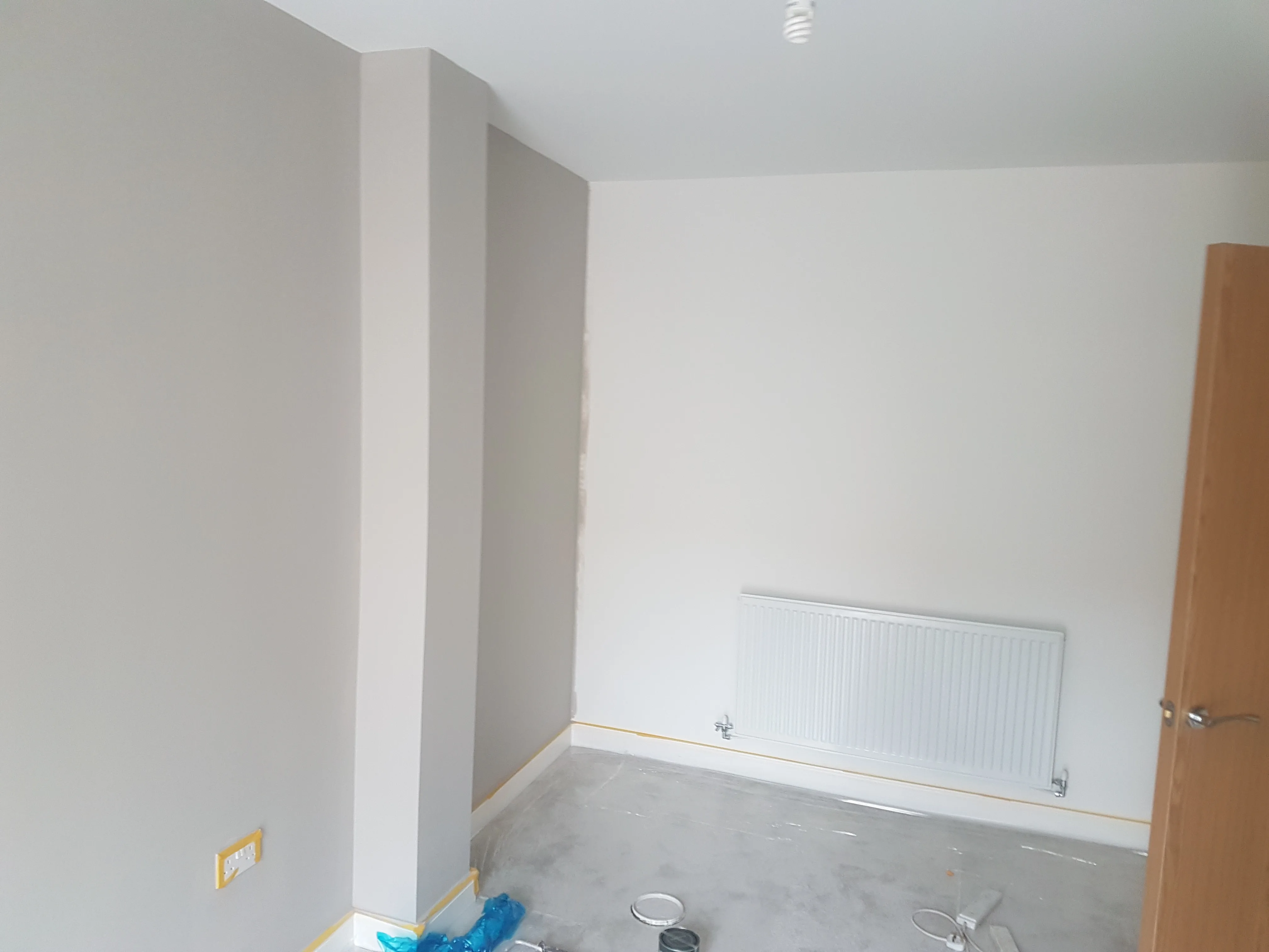 Interior painting in a room showing a freshly painted wall with minimal furniture