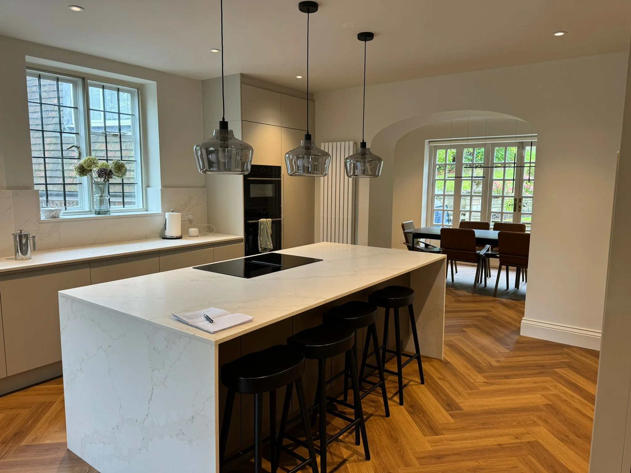 Modern kitchen refurbishment featuring marble countertop, pendant lights, and wooden flooring