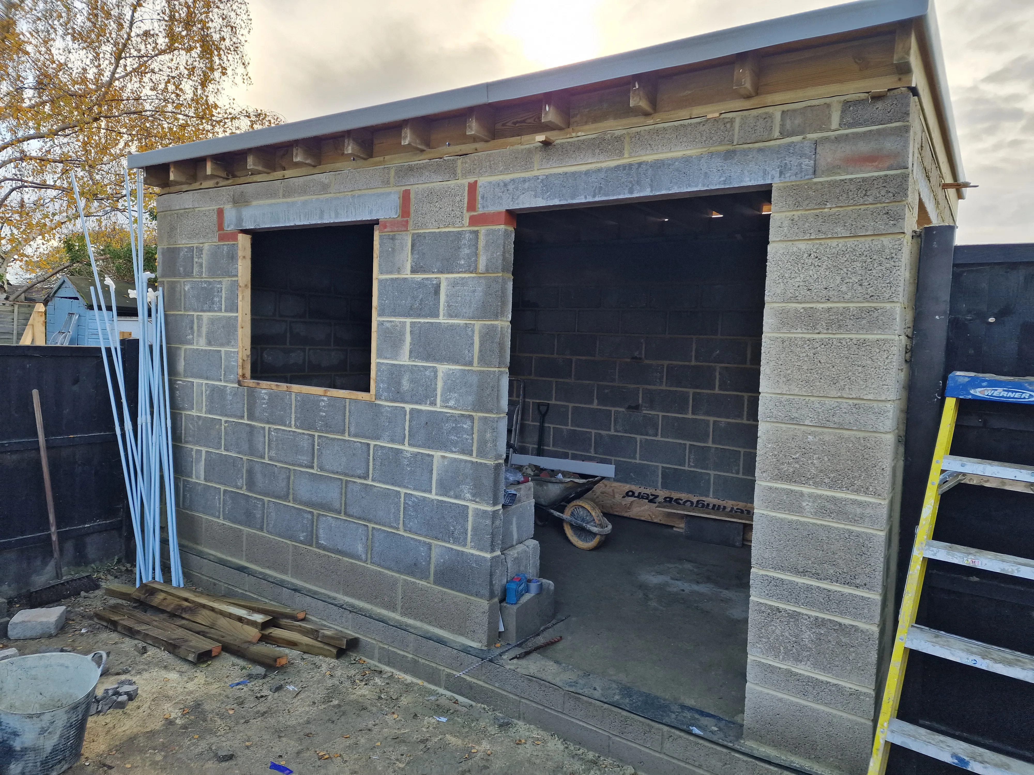 Under-construction garden outbuilding with exposed block walls and window openings