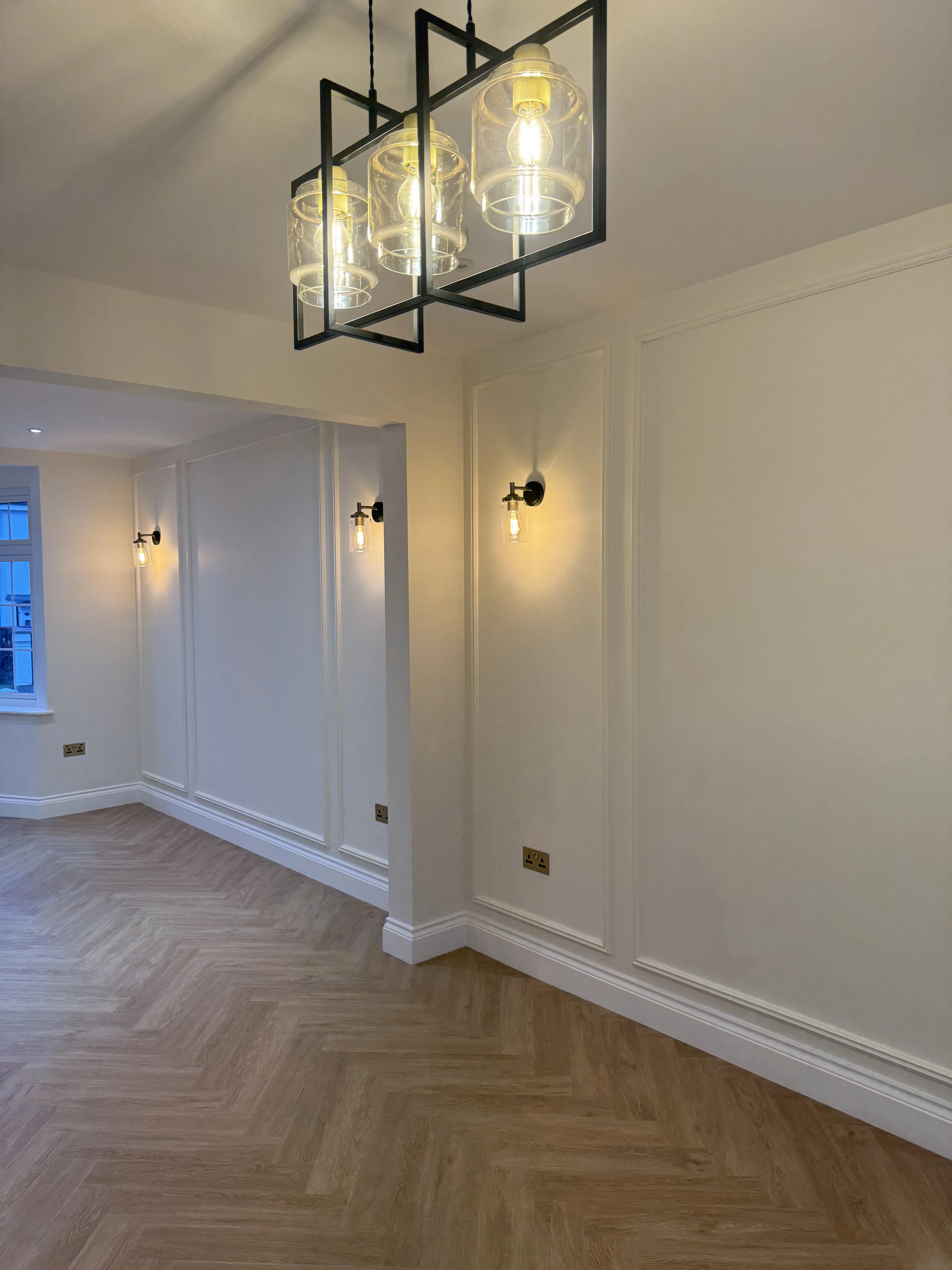 Interior view showing newly renovated room with modern lighting and herringbone wooden floor