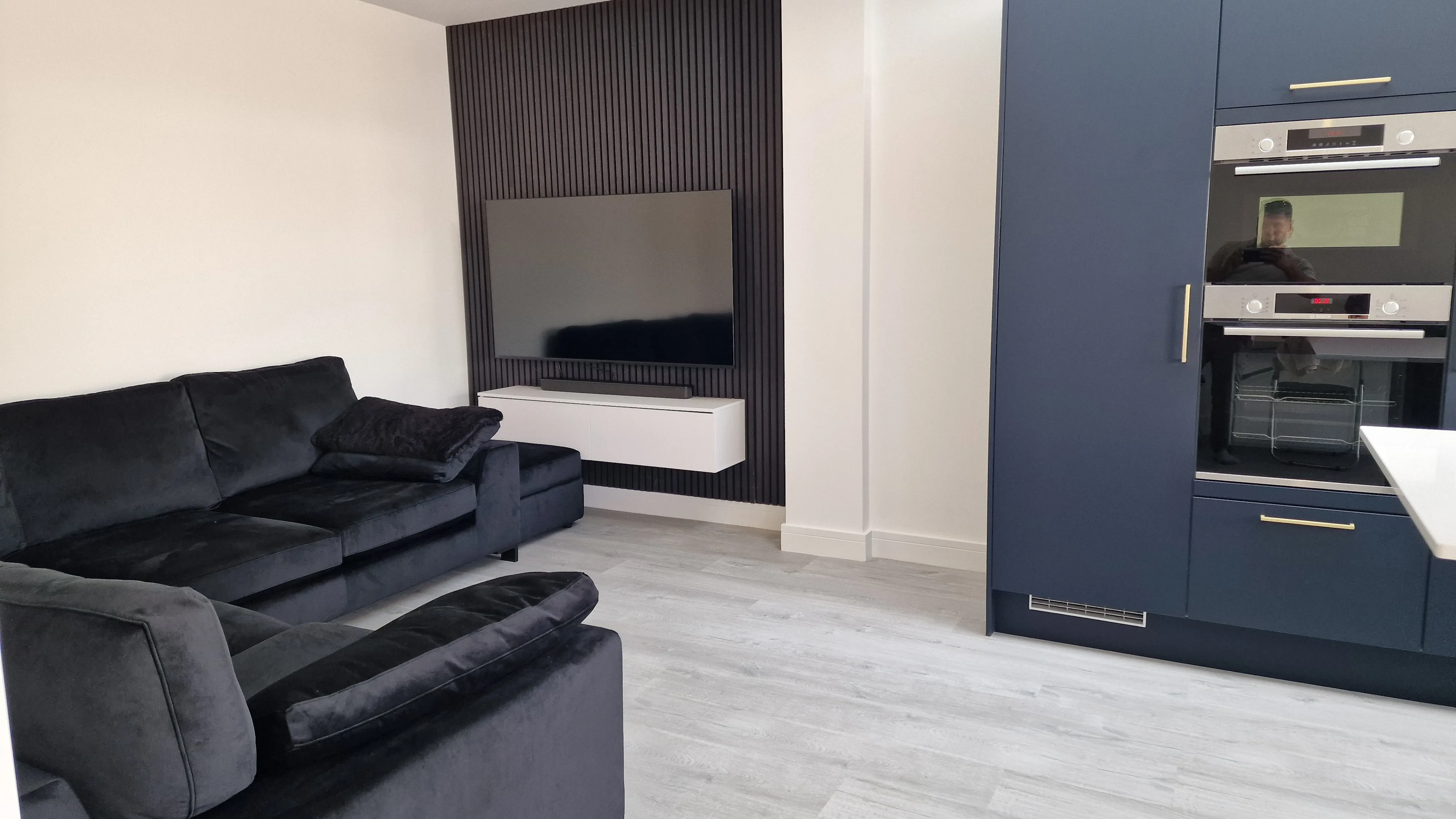Modern living room with a black sofa, wall-mounted TV, and stylish cabinetry
