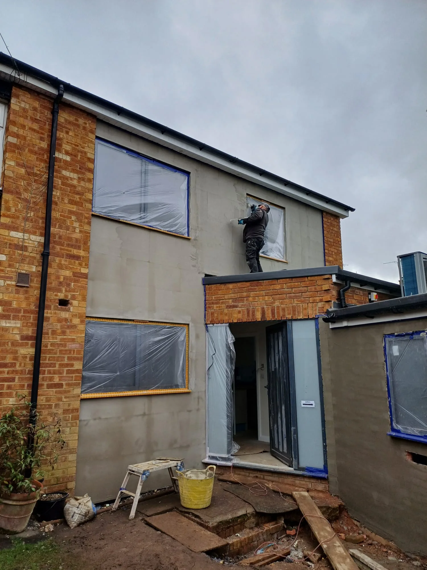 Worker applying exterior rendering to a building wall during renovation