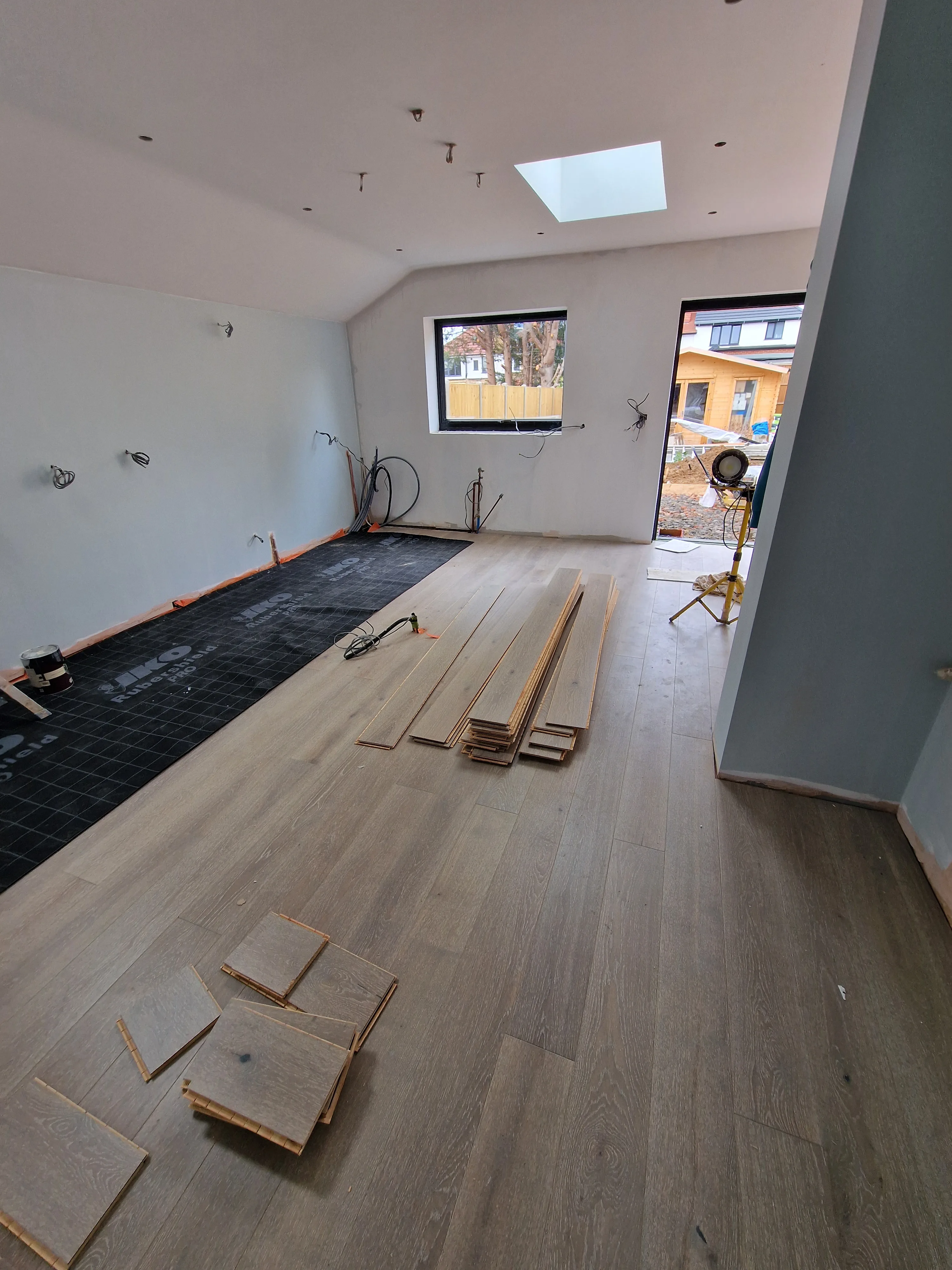 A room undergoing renovation with wooden floorboards, tools, and natural light coming from windows